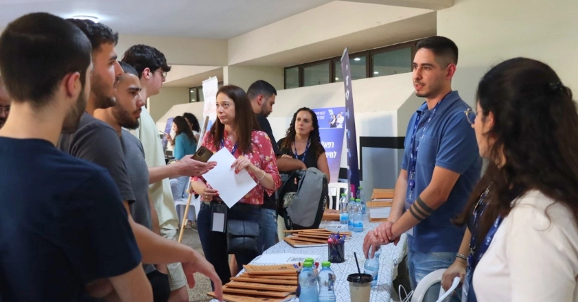 שולחן מסביבו מתעניינים ועומדים אנשים ושואלים שאלות